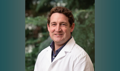 Oliver Harrison, DPhil headshot in white lab coat